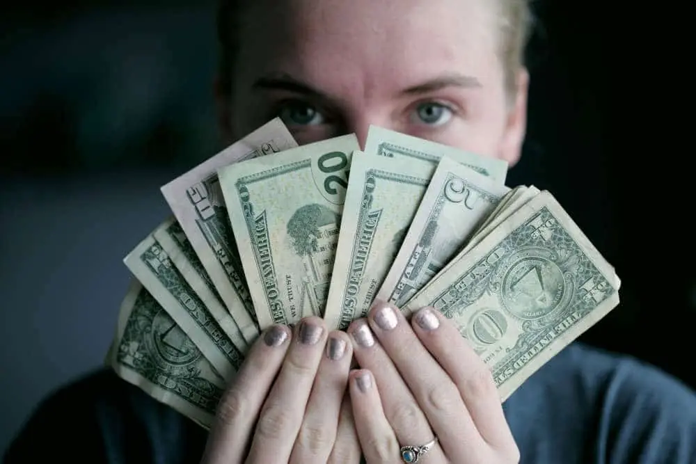 Woman holding money fanned out in front of her face