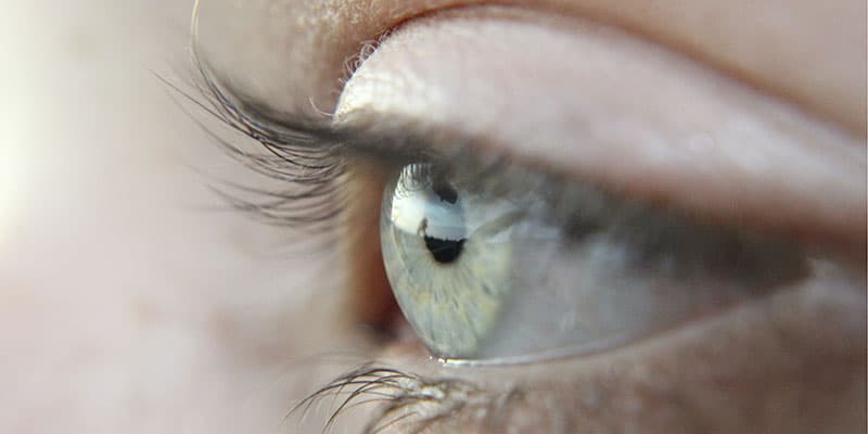 A very close up image of a pale green human eye.